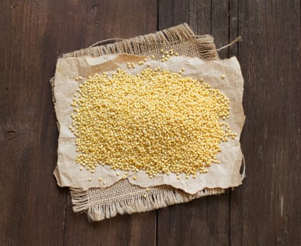 Raw millet on craft paper on dark wooden table