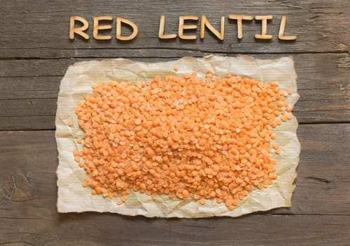 Red lentils with wooden word on a dark table