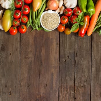 Quinoa in a bowl and fresh vegetables on a wooden table