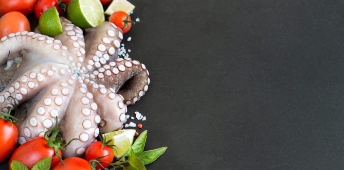 Raw octopus with lime, tomatoes and basil over dark background