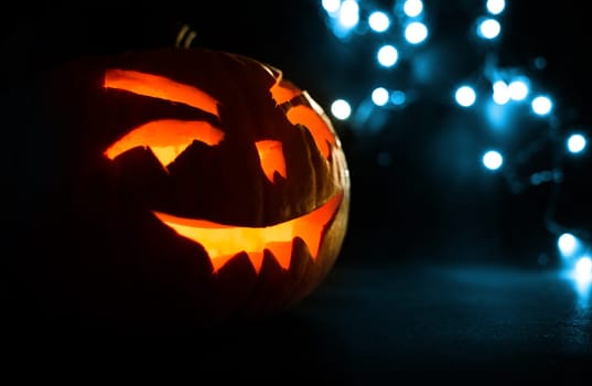 carved face of pumpkin glowing on halloween on blue bokeh light background