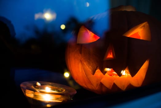 halloween pupkin symbol behind the home window with light at night reflectons