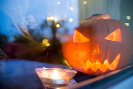 bright halloween pupkin symbol behind the home window with light reflectons