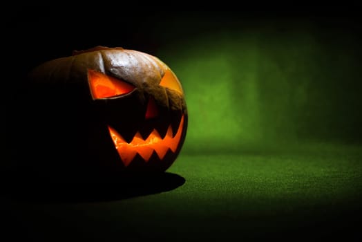 the carved face of pumpkin glowing on halloween on green background