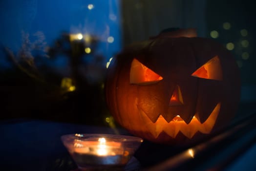 dark halloween pupkin symbol behind the home window with light reflectons
