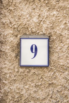 Ceramic number nine on the grey stone wall