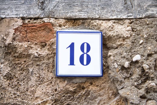 Ceramic number eighteen on the grey stone wall