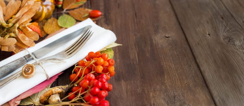 Autumn rustic table setting with berries, leaves, muchrooms and nuts on wood