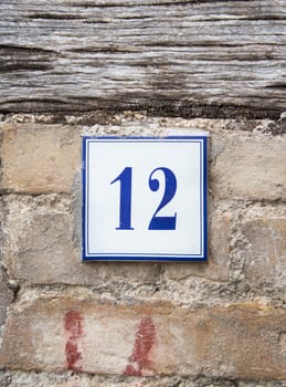 Ceramic number twelve on the grey stone wall