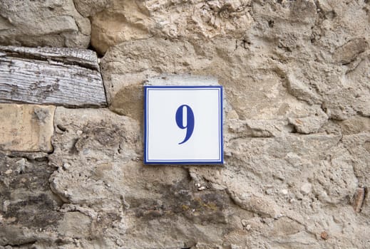 Ceramic number nine on the grey stone wall