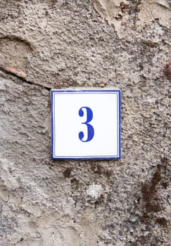 Ceramic number three on the grey stone wall
