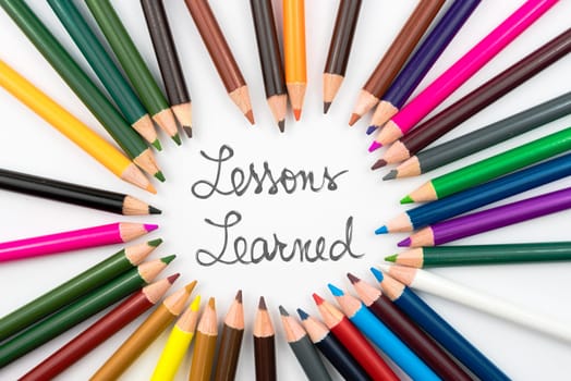 Colouring pencils in circle arrangement with message Lessons Learned, education concept