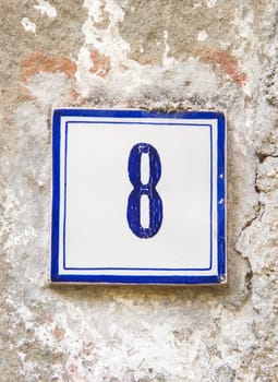 Ceramic number eight on the grey stone wall