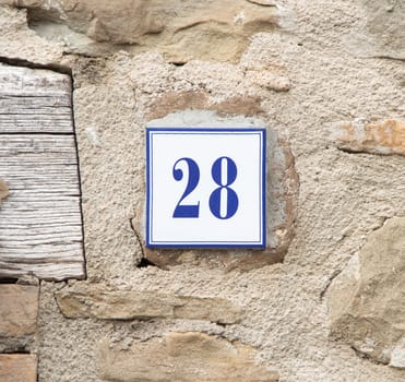 Ceramic number twenty eight on the grey stone wall