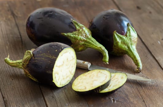 Fresh Raw eggplants with knife on the wood background