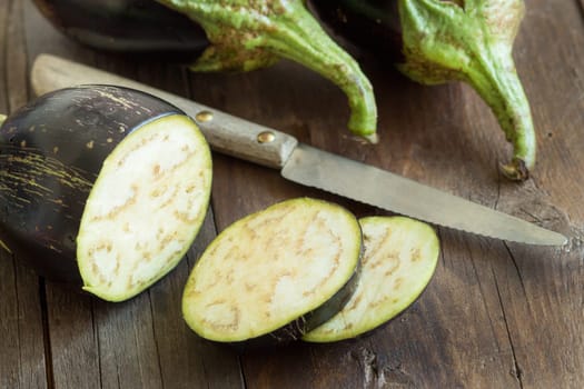 Fresh Raw eggplants with knife on the wood background