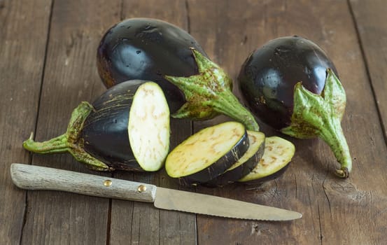Fresh Raw eggplants with knife on the wood background