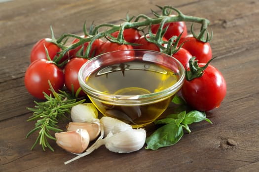 Olive oil, herbs, garlic and tomatoes on the wooden table