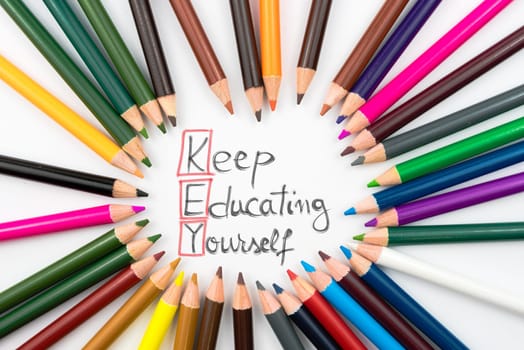 Colouring pencils in circle arrangement with message KEY Keep Educating Yourself, education concept