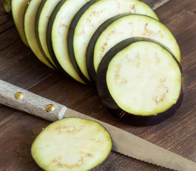 Fresh Raw eggplants with knife on the wood background