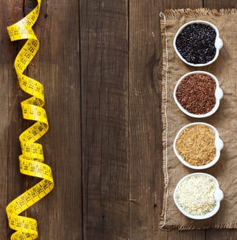 Black, red wild rice, basmati and unpolished whole rice in bowls on wooden table