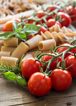 Pasta, garlic, herbs and tomatoes on the wooden table