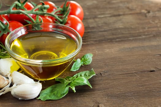 Olive oil, herbs, garlic and tomatoes on the wooden table
