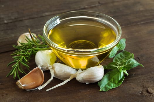 Olive oil, herbs and garlic on the wooden table