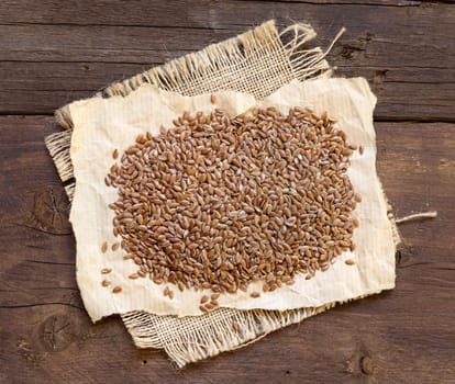 Pile of flax seeds on a wooden background