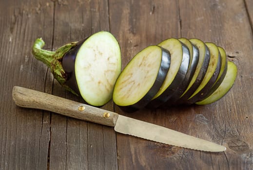 Fresh Raw eggplants with knife on the wood background