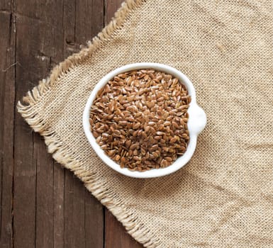 Flax seeds in a bowl on a wooden background