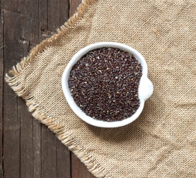Psyllium seeds in a bowl on a wooden table