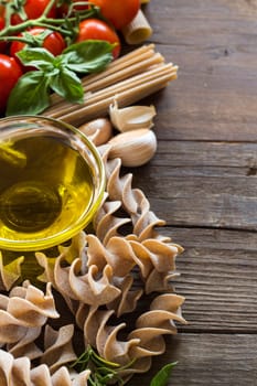 Olive oil, pasta, garlic and tomatoes on the wooden table