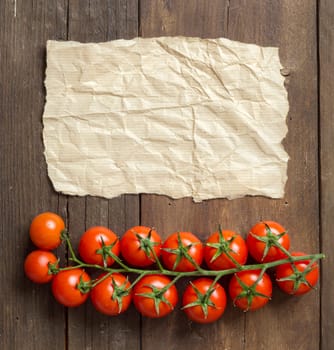 Cherry tomatoes and craft paper on wooden background