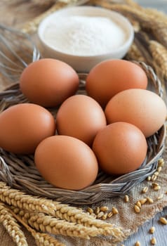 Chicken eggs, wheat and flour on the old wood