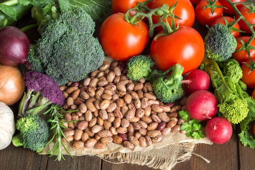 Pile of pinto beans and vegetables on a wooden bacground