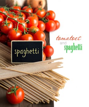 Spaghetti, tomatoes and small chalkboard on old vintage wooden table