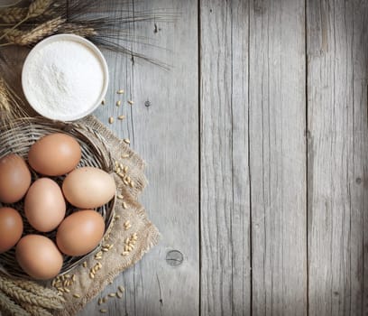 Chicken eggs, wheat and flour on the old wood