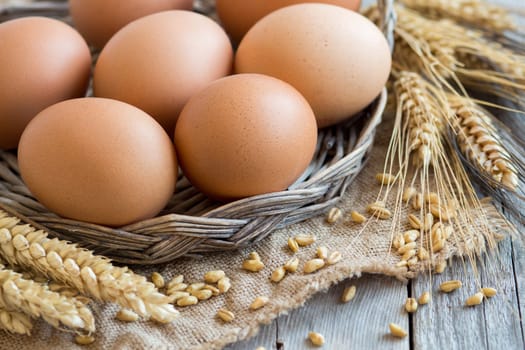 Chicken eggs and wheat on the old wooden table