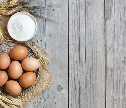 Chicken eggs, wheat and flour on the old wood