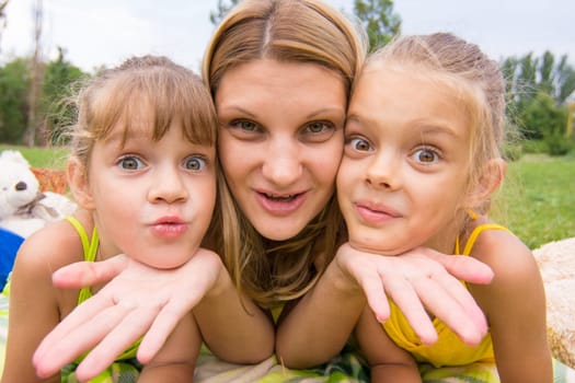 Two girls resting her head on her mother's palm and fun look into the frame