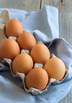 Chicken eggs in the box on the blue napkin