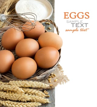 Chicken eggs, wheat and flour on the old wood