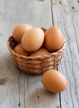 Chicken eggs in a basket on a wooden table