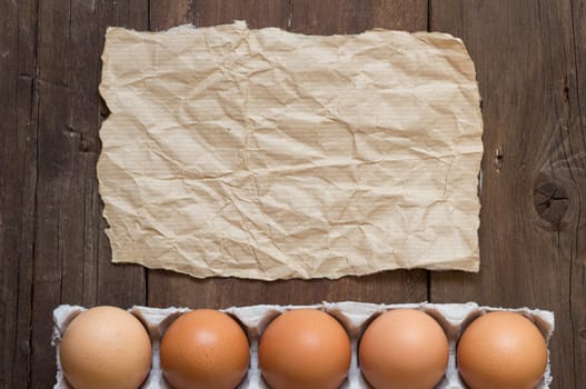 Chicken eggs in the package and craft paper on the old wooden table
