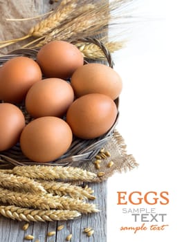 Chicken eggs and wheat on the old wood