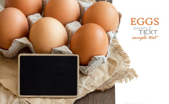 Chicken eggs in the package and small chalkboard close up