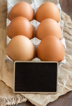 Chicken eggs in the package and small chalkboard close up