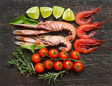 Raw langoustines and shrimps with vegetables on the dark wood