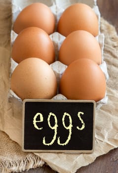 Chicken eggs in the package and small chalkboard close up